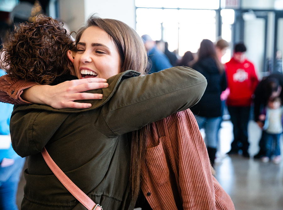 Two women embracing and laughing in a church lobby
